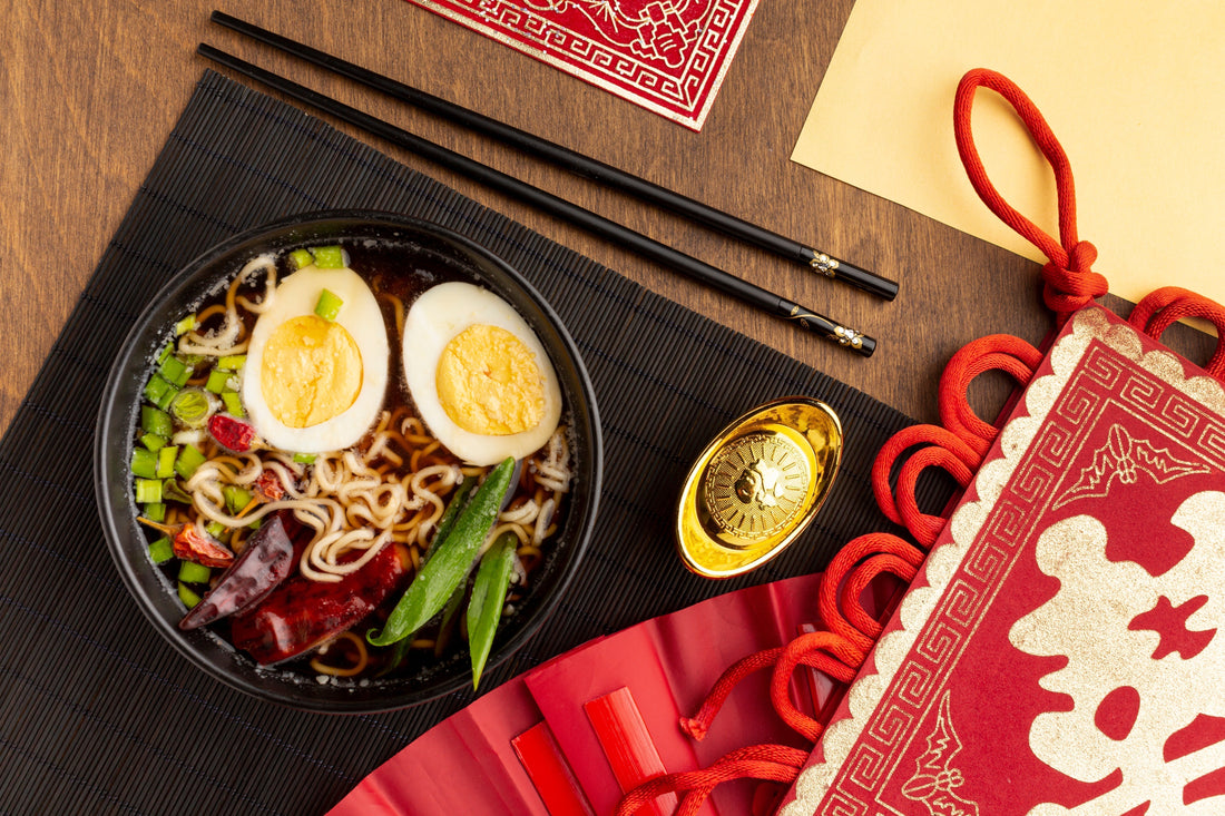 A bowl of authentic long-life noodles with wooden chopsticks on a festive table setting for Chinese New Year 2026.